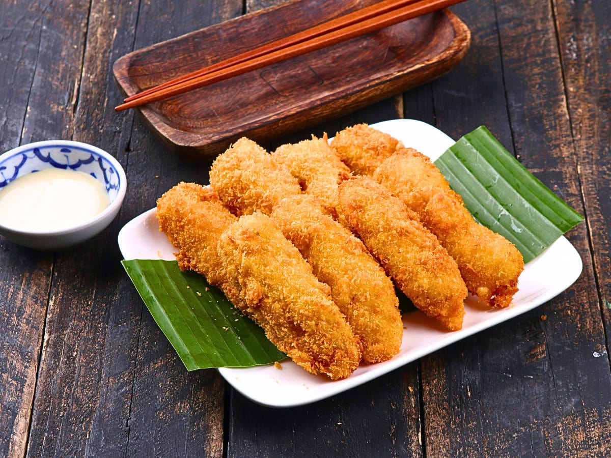Golden fried banana fritters served with dipping sauce, similar to Surinamese bakabana made with battered and fried plantain.
