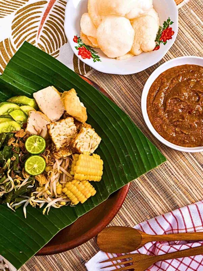 a dish known as gado gado in Indonesia is a melange of vegetable topped with spicy peanut sauce. Served here on banana leaf accompanied by some prawn crackers