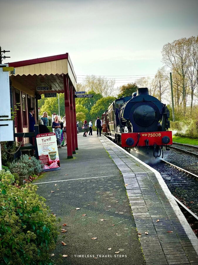 Passengers waiting at Bodiam Railway Station as a steam train arrives, Kent and East Sussex Railway