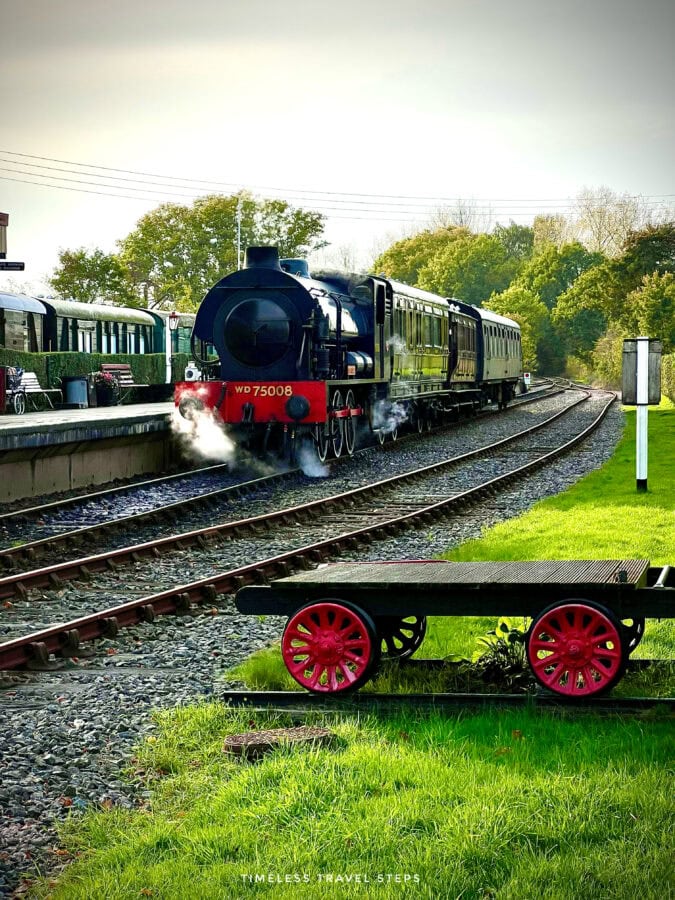 Heritage steam locomotive arriving at Bodiam Railway Station, emitting smoke as it pulls up to the platform