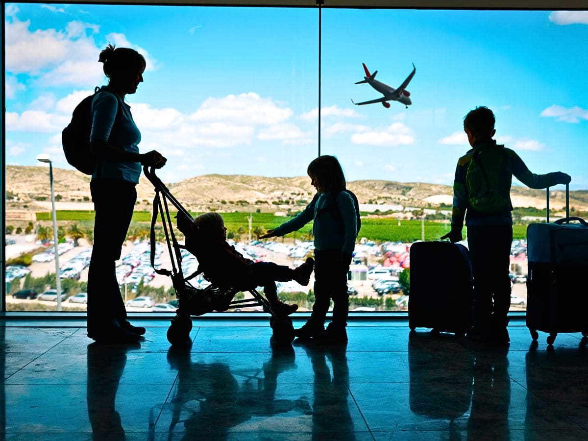 baby in stroller, mum with a backpack, and two more children at the airport