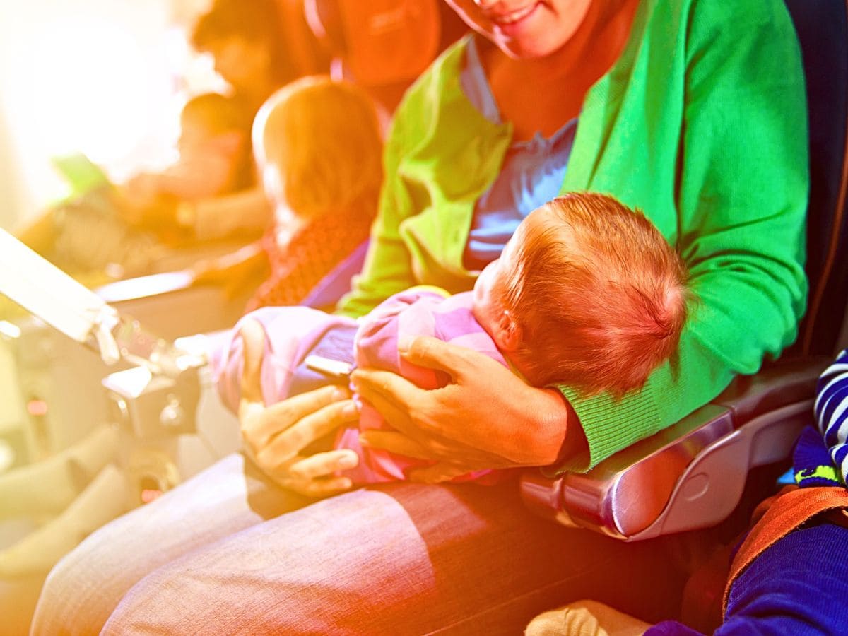 a lady with a baby in her arms inside the airplane