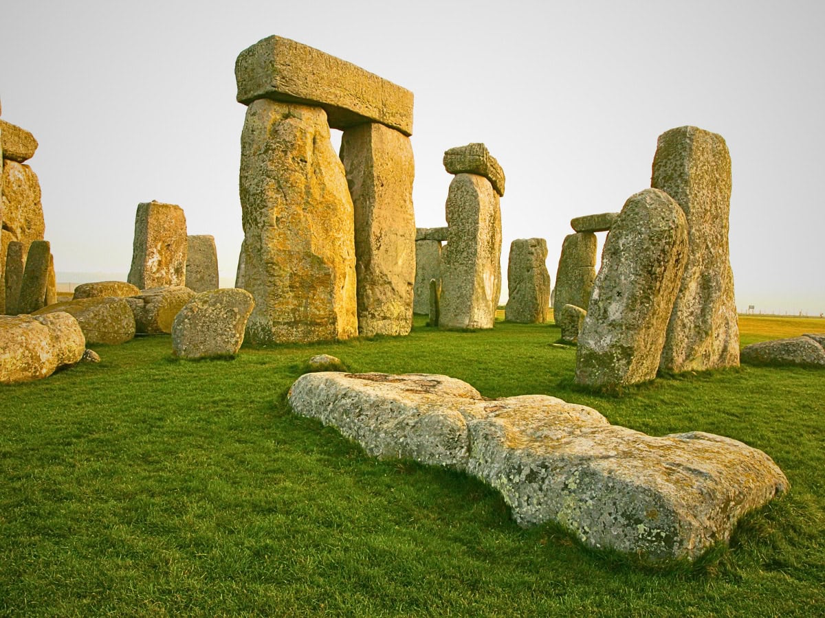 Stonehenge in early morning light, with a soft golden glow casting warmth over the ancient stones.