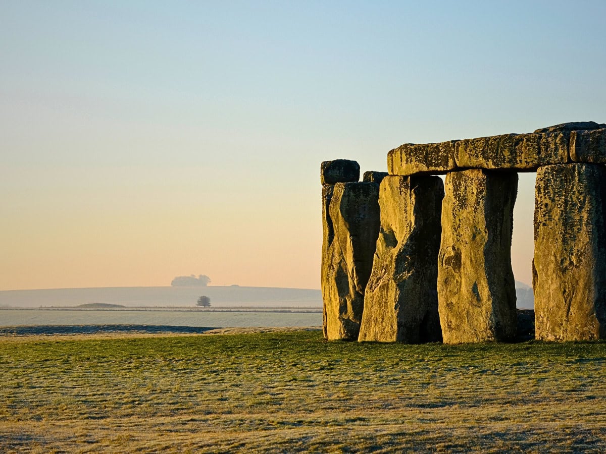 Stonehenge at sunrise, with a partial view of the gigantic stones set against the vast expanse of Salisbury Plain.