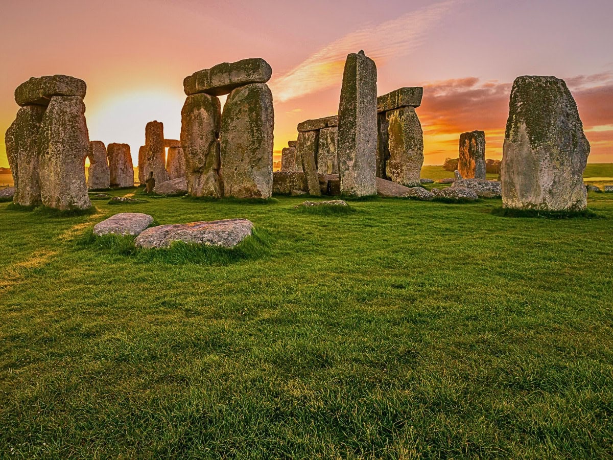 Stonehenge at sunrise, bathed in vibrant colours as the sun rises over the prehistoric stone circle.
