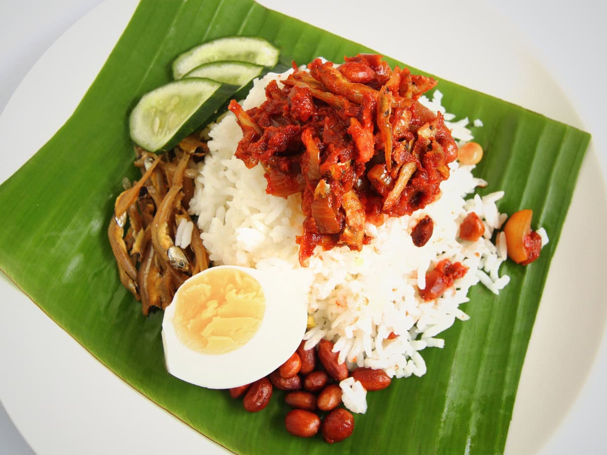 Classic Malaysian nasi lemak with coconut-infused rice, sambal, boiled egg, cucumber, roasted peanuts, and crispy anchovies.