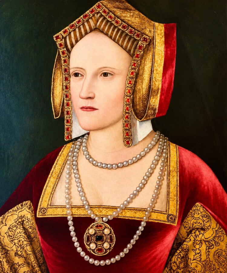 Katherine of Aragon wearing a richly decorated Tudor gown, jewelled gable hood and pearl necklaces.